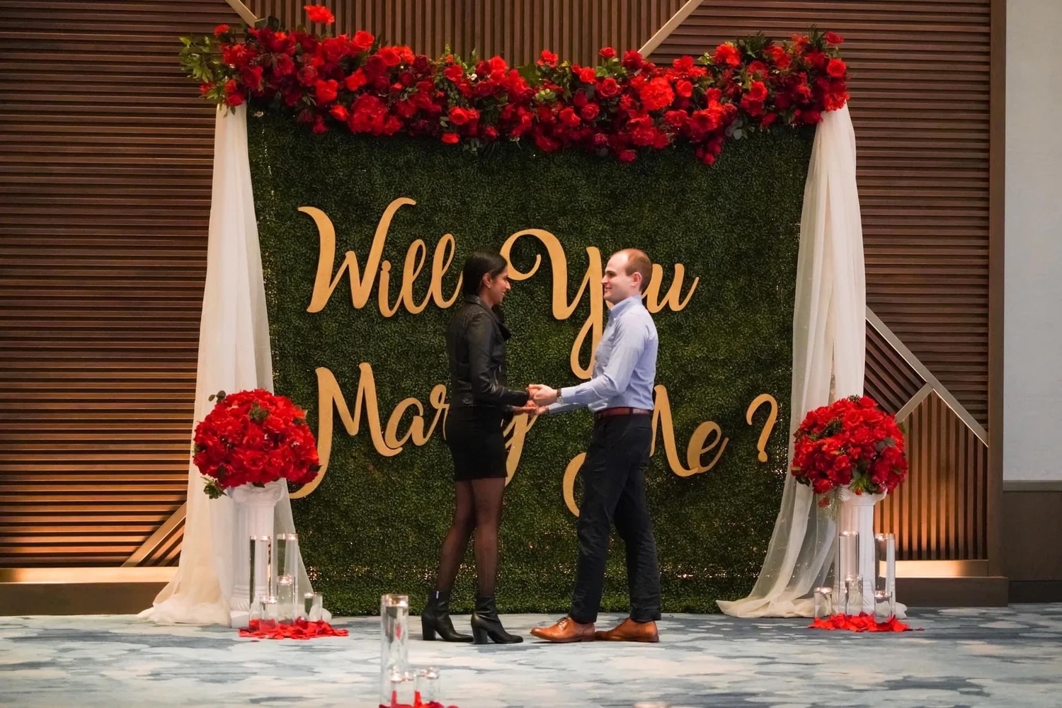 A proposal set with a rose installation, drapery, and candlelight